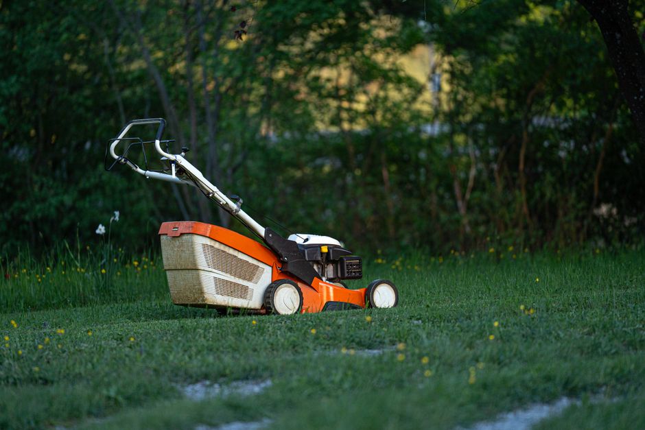 Professional pushing a lawn mower across a residential yard